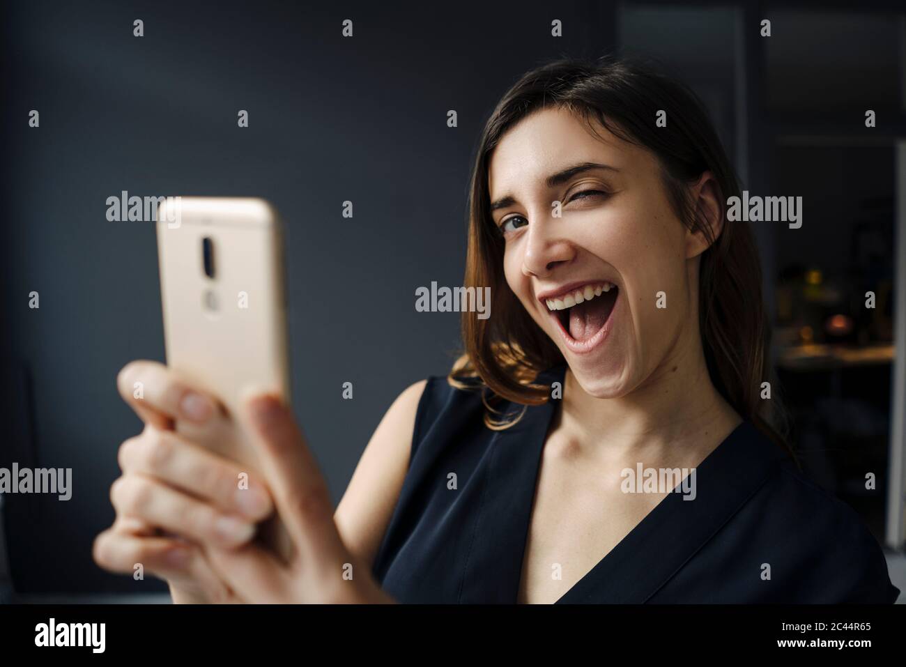 Ritratto di giovane donna con smartphone che tira volti divertenti Foto Stock