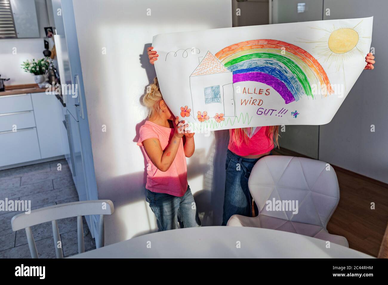 Ragazze che tengono il disegno davanti ai volti a casa Foto Stock