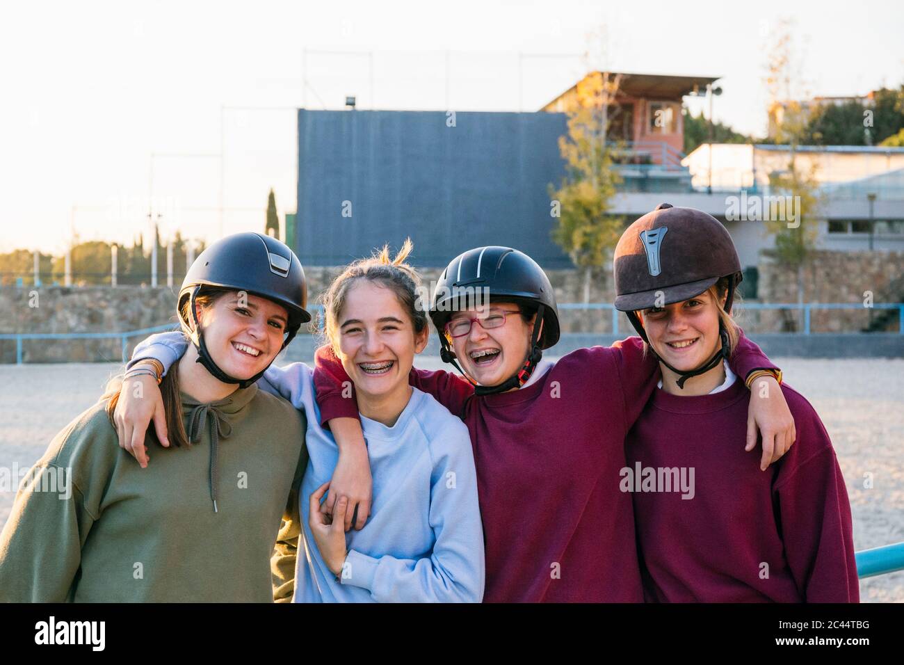 Ritratto di allegri scacciatori femminili in piedi insieme contro il terreno di allenamento in giornata di sole Foto Stock