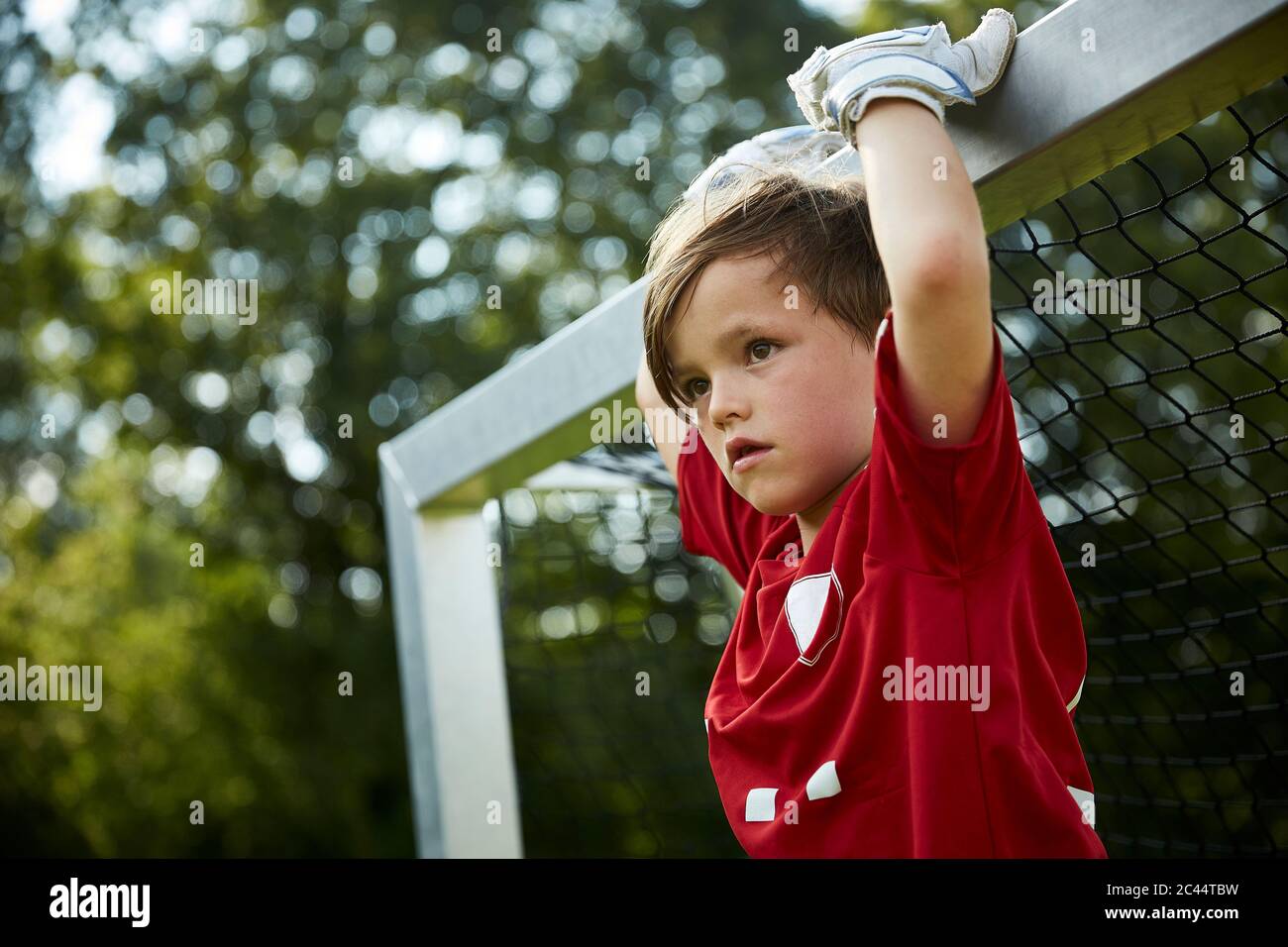 Ragazzo di calcio premuroso che tiene posto di obiettivo sul campo Foto Stock