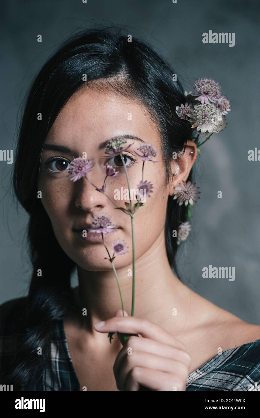 Bella giovane donna che tiene e porta fiori Foto Stock
