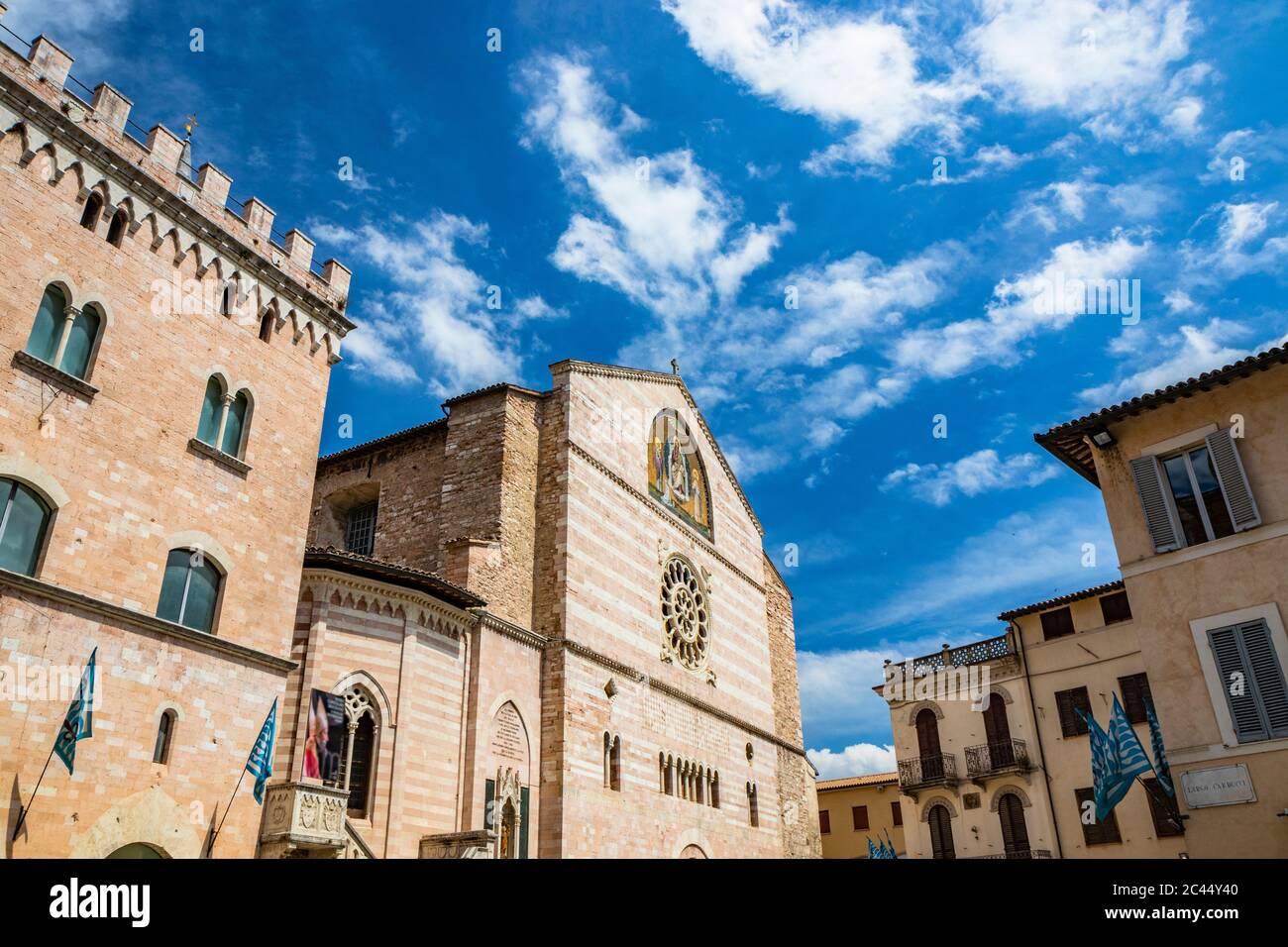 Il Duomo di San Feliciano nella piazza di Foligno. La facciata principale, con il rosone, le finestre a bifore, gli archi e le colonne. Le bandiere blu Foto Stock