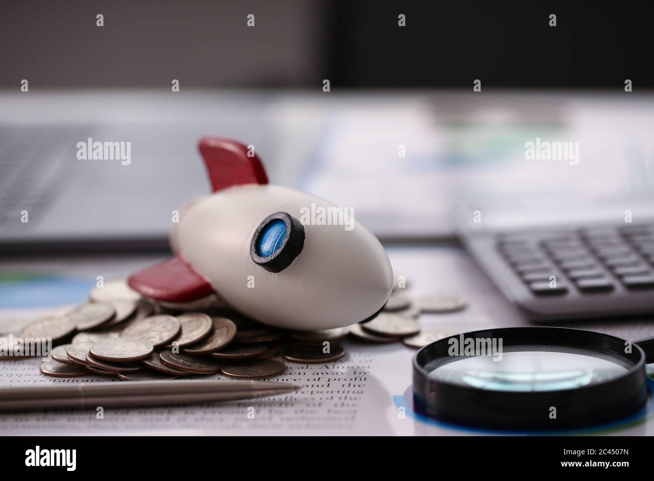 Razzo giocattolo, monete, penna d'argento e lente d'ingrandimento sul tavolo Foto Stock