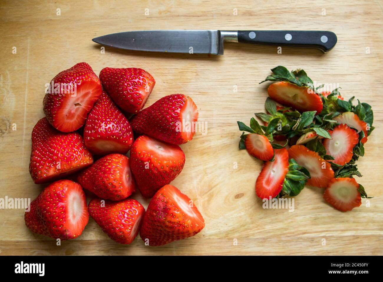 Fragole britanniche fresche su un tagliere affettato con un coltello Foto Stock