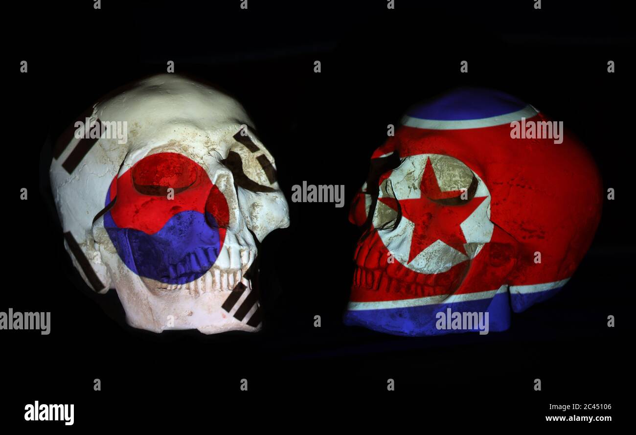 Bandiere sudcoreane e nordcoreane proiettate su teschi umani dall'aspetto realistico. Isolato su uno sfondo nero. Foto Stock