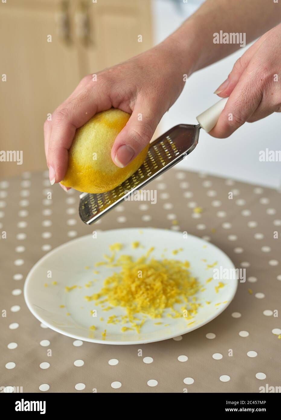 Primo piano di donna che strofina la scorza di limone sul grattugia Foto Stock