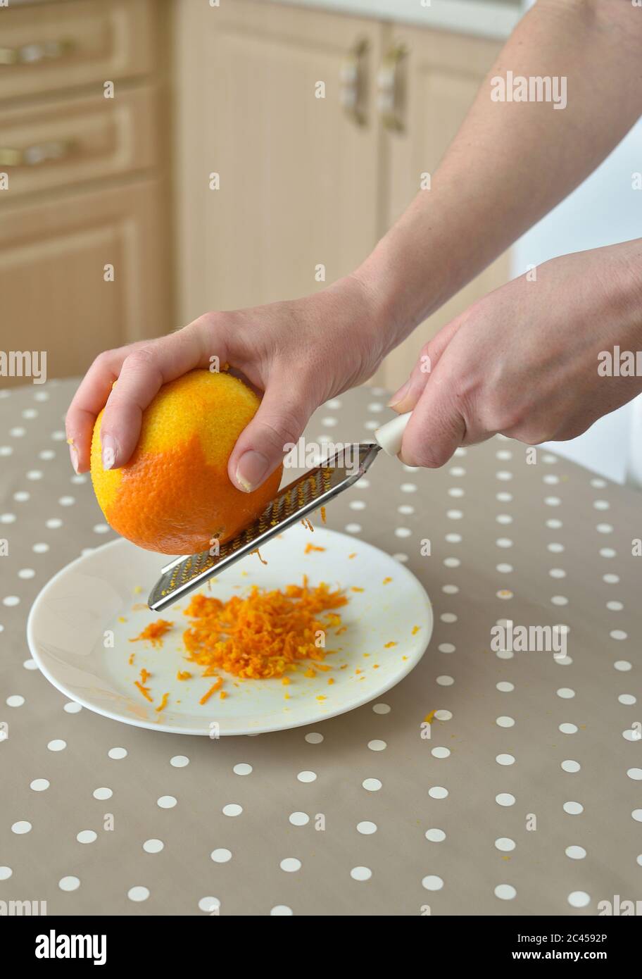 Primo piano di donna che sfrega la scorza d'arancia sul grater Foto Stock