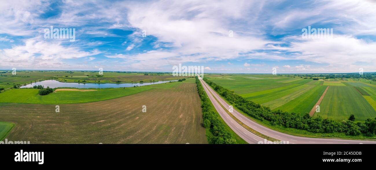Paesaggio rurale estivo con cielo bellissimo in una giornata di sole. Vista sui campi coltivabili, sull'autostrada e sul lago. Vista aerea. Panorama da 21 immagini Foto Stock