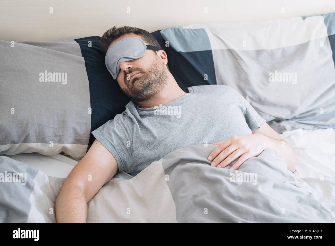Ritratto uomo a letto indossando maschera occhio addormentato sentirsi a proprio agio Foto Stock