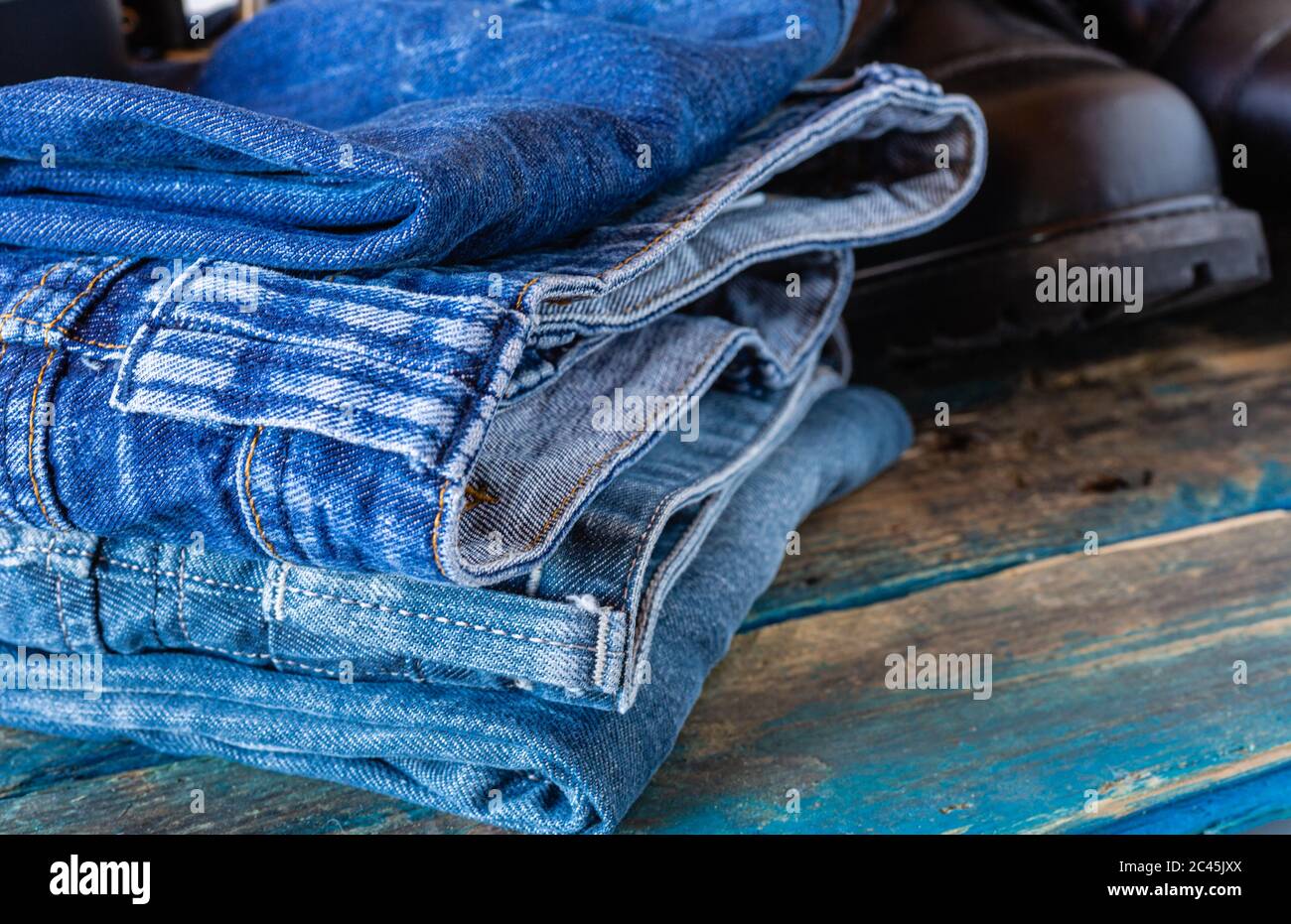 Jeans blu e scarpe da lavoro. Pantaloni su vecchie tavole. Scarpe in pelle nera. Foto Stock