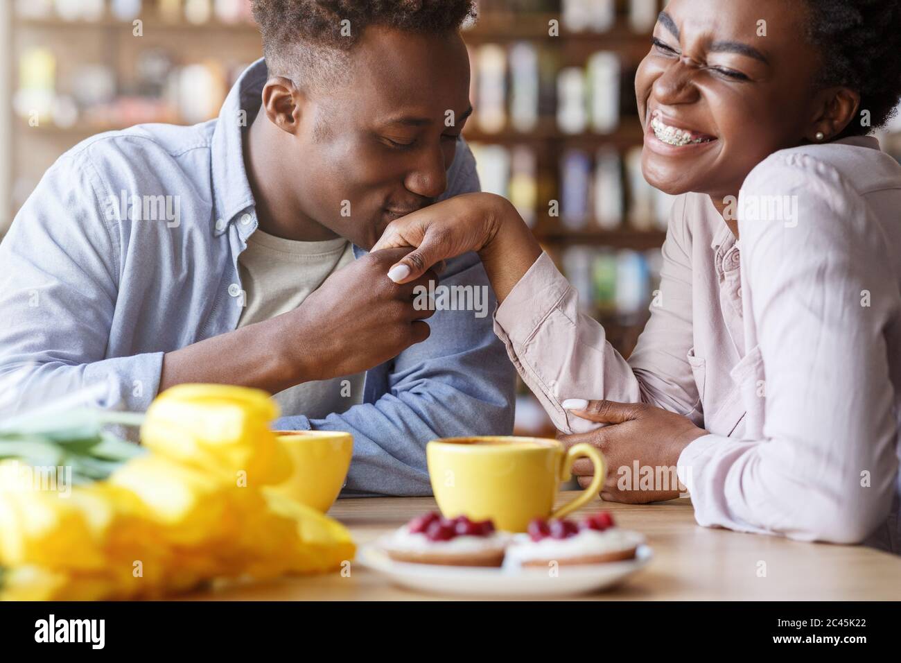 Bell'afro-americano ragazzo baciare la sua mano girlfriends al bar Foto Stock
