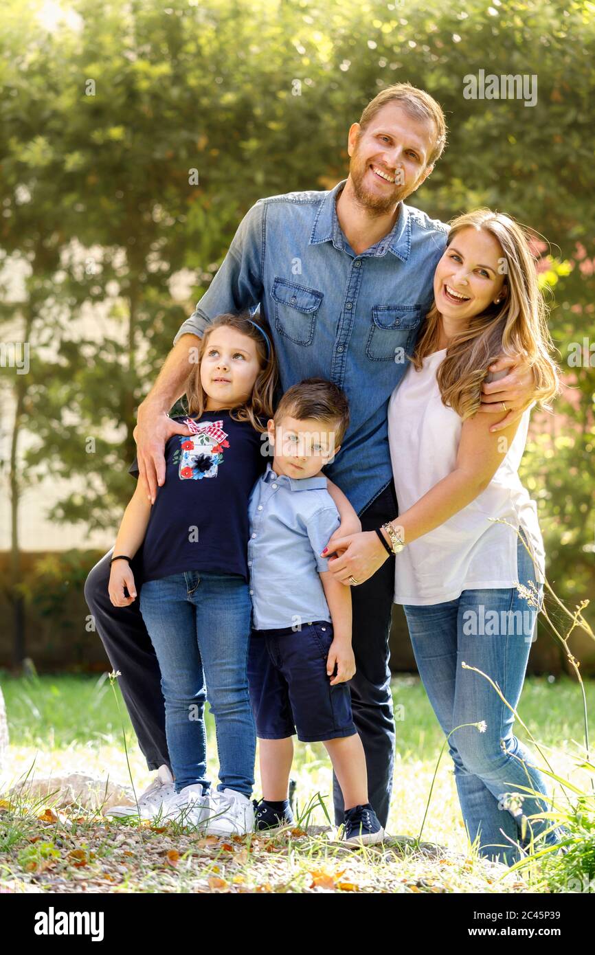 Ritratto di famiglia, uomo e donna in piedi all'aperto con ragazzo e ragazza, sorridendo alla macchina fotografica. Foto Stock
