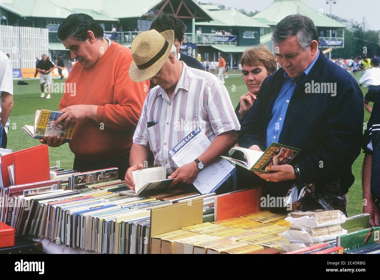 Collezionisti di libri di cricket che esplorano una bancarella durante una pausa nella partita di cricket. Hastings, Sussex orientale, Inghilterra, Regno Unito Foto Stock