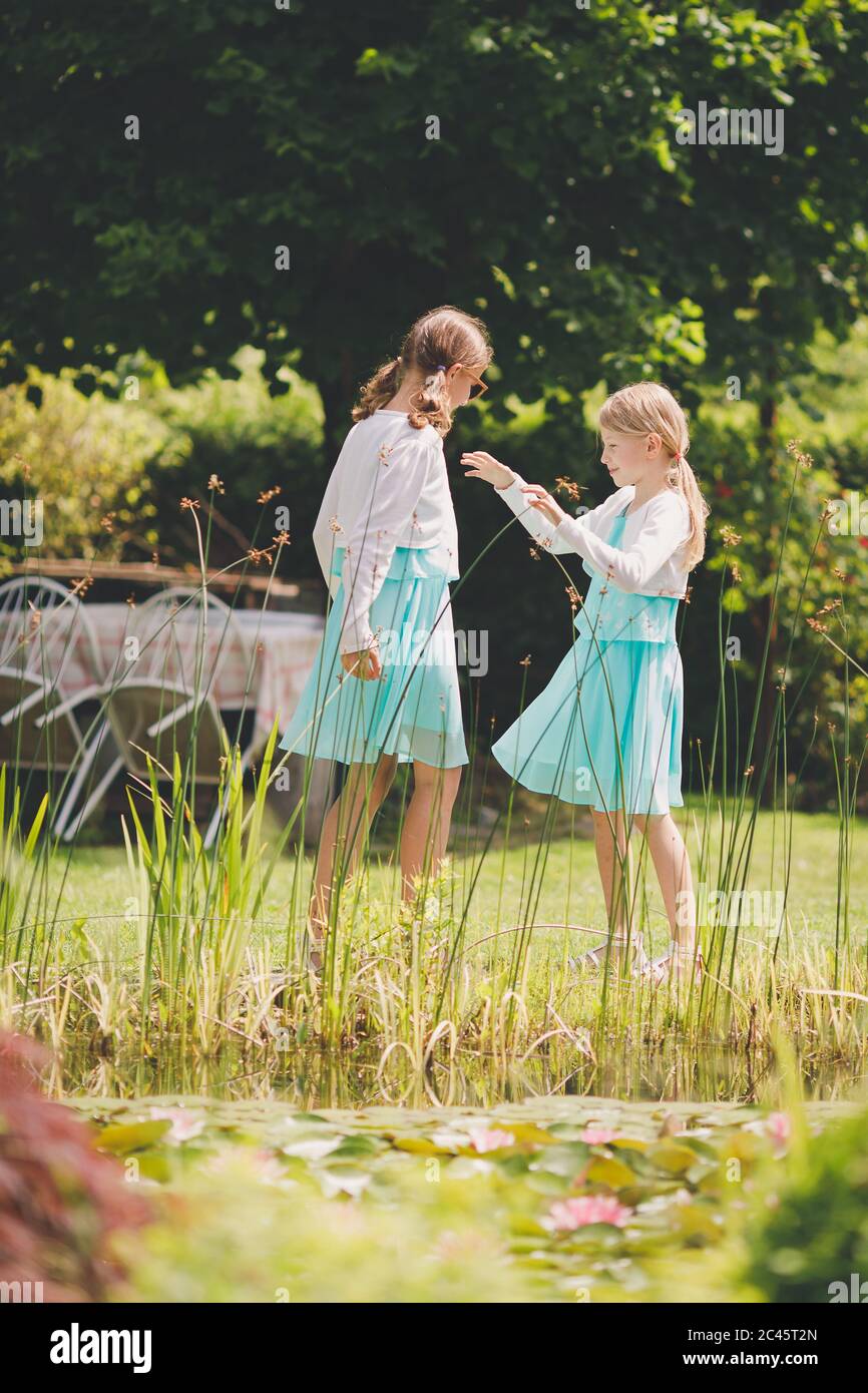 Due ragazze caucasiche che giocano a mani che si battono in giardino verde Foto Stock