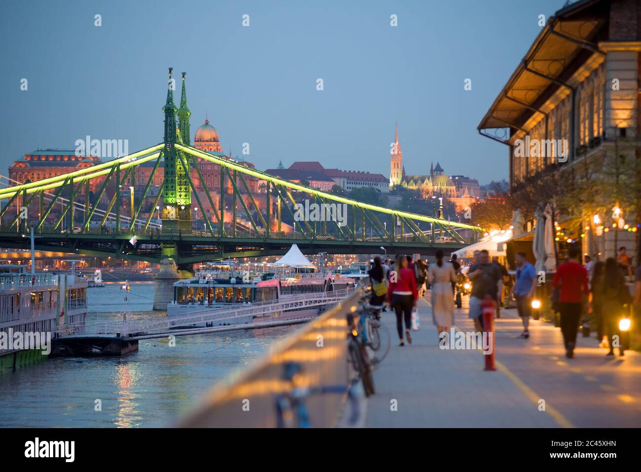 Lungomare di Budapest di notte, Ponte della libertà, persone a piedi Foto Stock