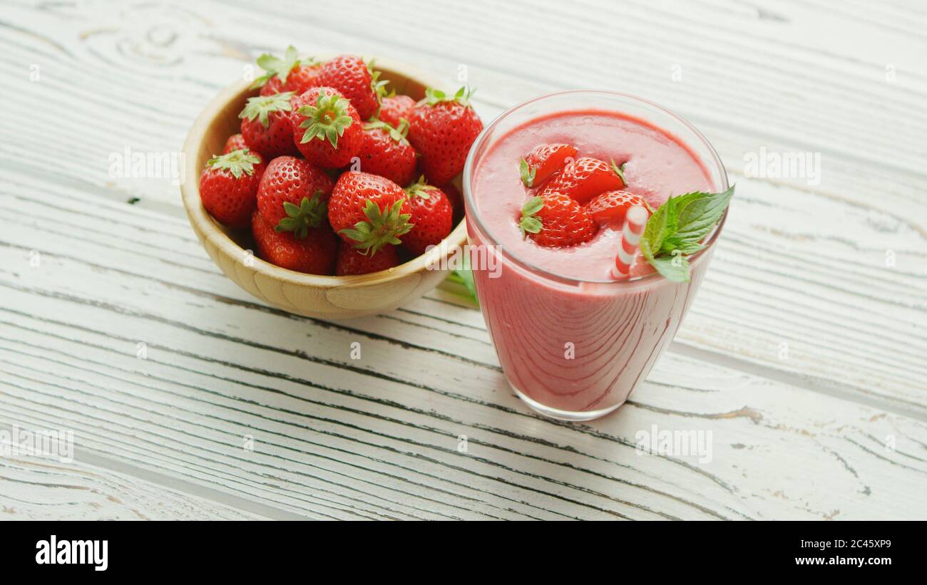 Vetro con i frullati e la tazza di fragole Foto Stock