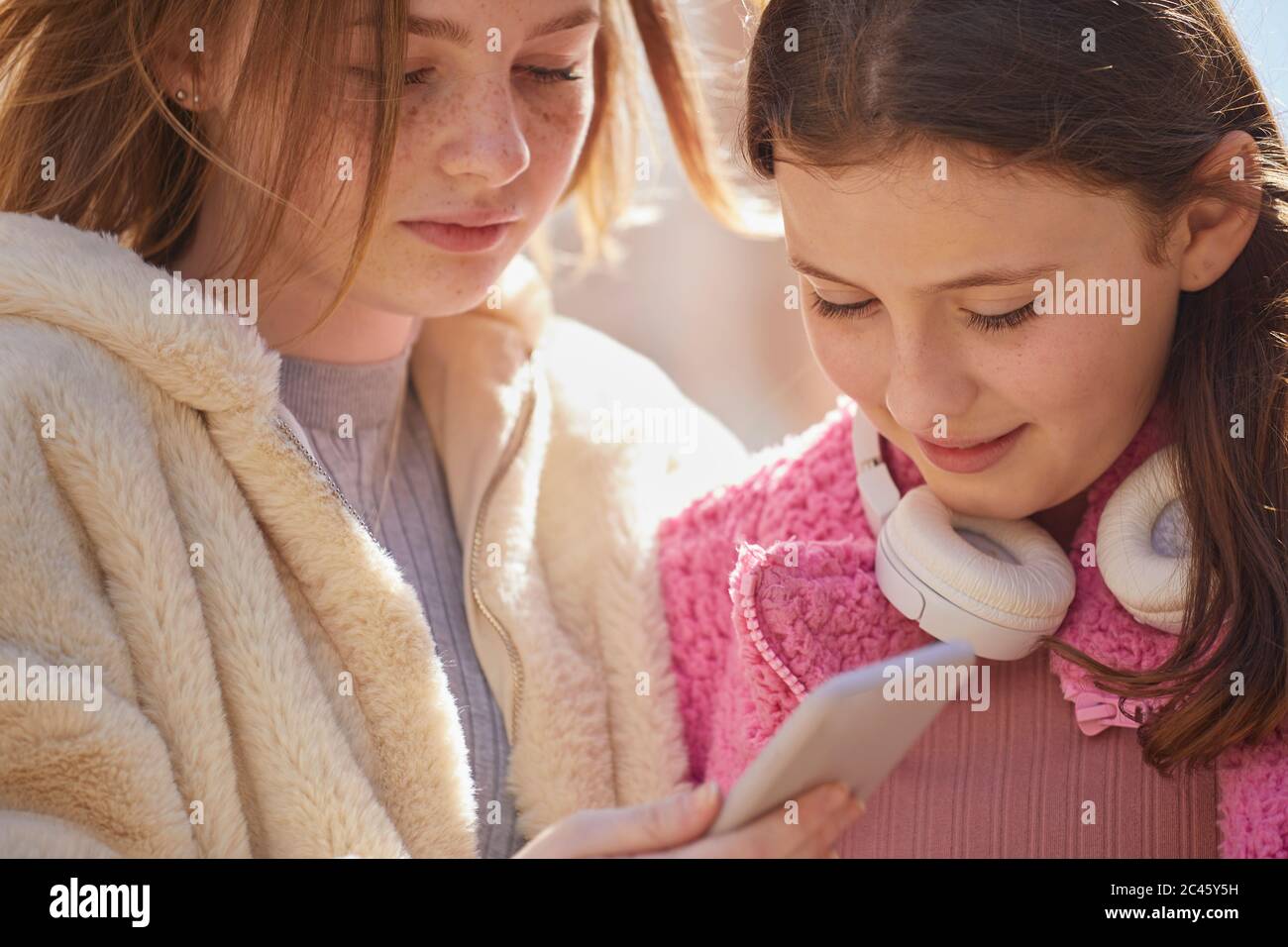 Due ragazze adolescenti in un centro commerciale, controllando i loro telefoni cellulari. Foto Stock