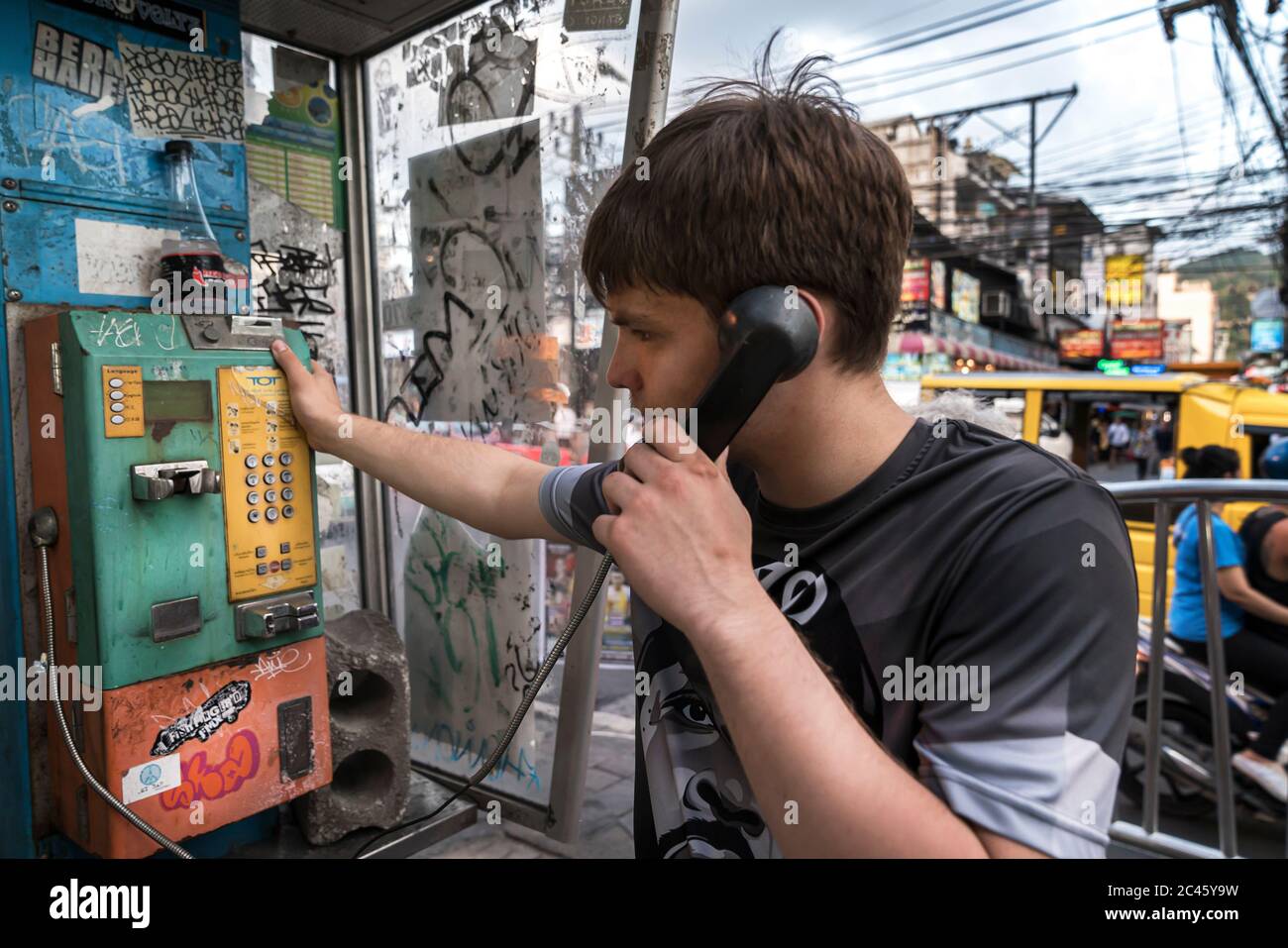 Thailandia, Phuket, 15 aprile 2020: Ragazzo che parla su un telefono di strada, via tailandese Vibe su Bangla strada, vita reale. Foto Stock