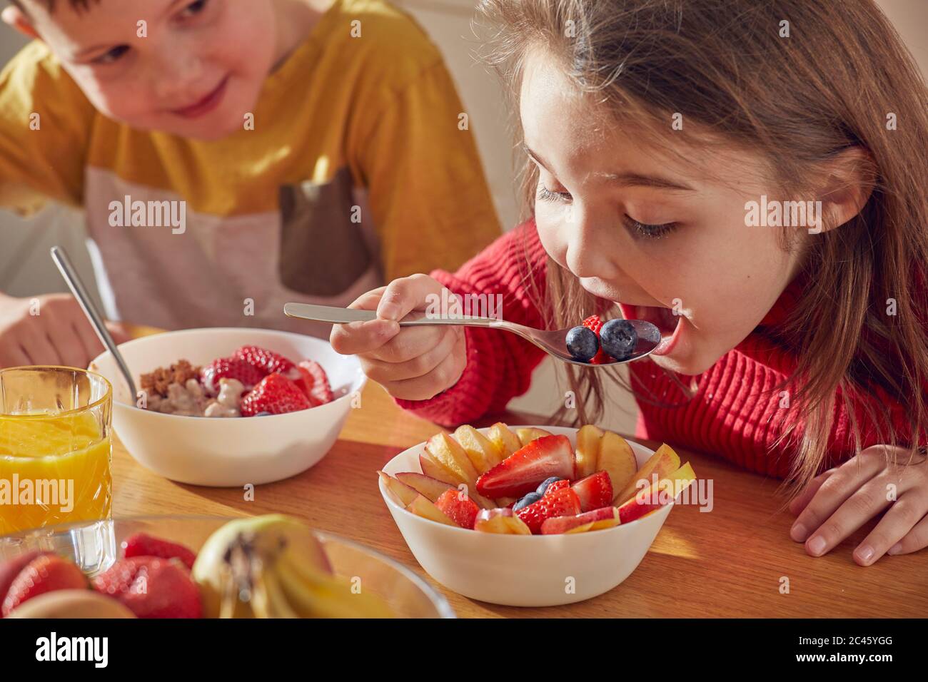 Ragazzo e ragazza seduti al tavolo da cucina, mangiando la colazione. Foto Stock