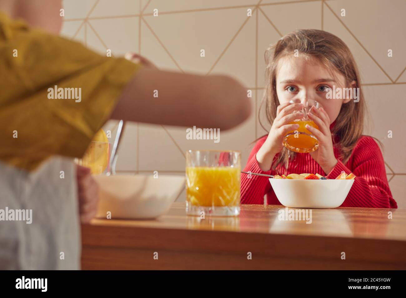Ragazzo e ragazza seduti al tavolo da cucina, mangiando la colazione. Foto Stock