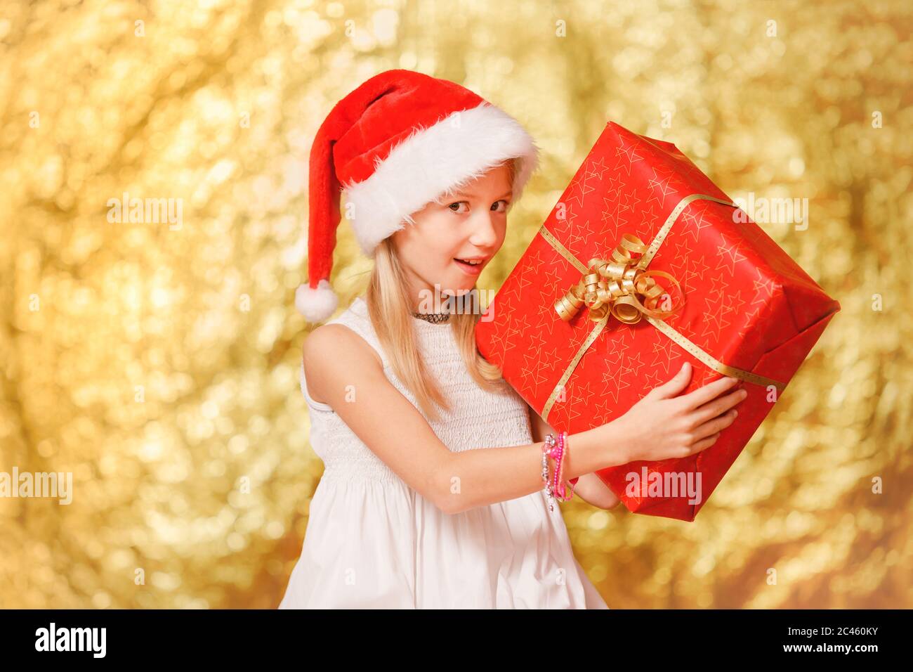 Giovane ragazza, età della scuola primaria, regalo di Natale, indossare cappello di Natale di fronte al CH festivo Foto Stock