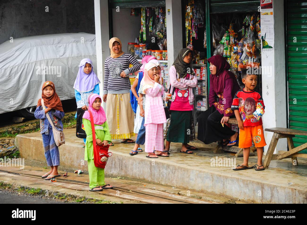 Bambini indonesiani che guardano la macchina fotografica con i volti divertenti fuori dal negozio. Giava Occidentale, Indonesia Foto Stock