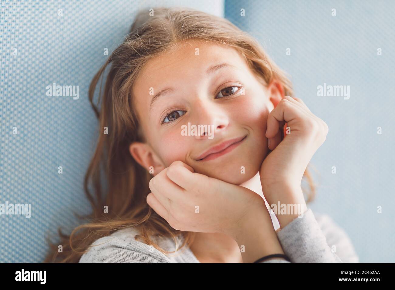 Ritratto luminoso e arioso di giovane ragazza sorridente davanti alla fotocamera su sfondo blu Foto Stock