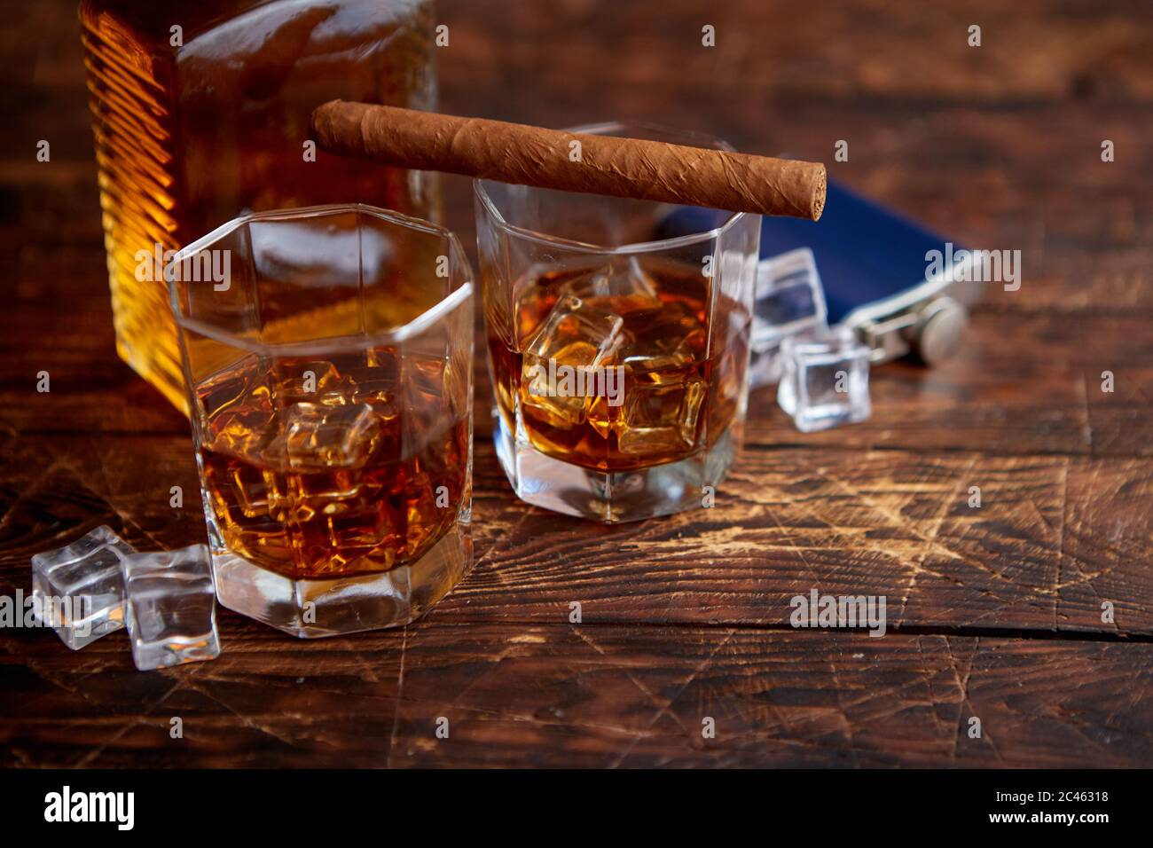 Bottiglia di whisky con due bicchieri e sigaro cubano posto su un rustico tavolo in legno Foto Stock