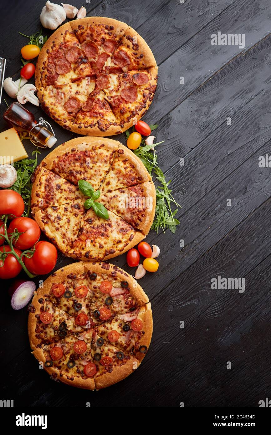 Servito fresco, tre diverse pizze collocato tra gustosi ingredienti. Vista superiore Foto Stock
