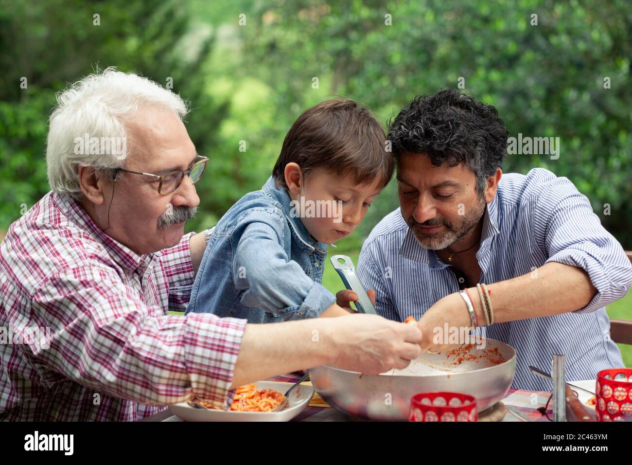 Tre generazioni della famiglia maschio gustando un pasto insieme Foto Stock