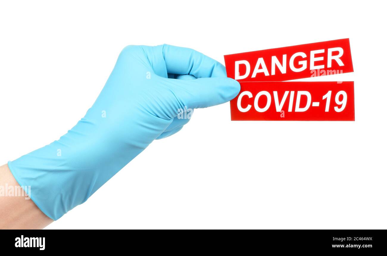 La mano della donna in guanti medici tiene il segno rosso pericolo Covid-19 su sfondo bianco Foto Stock