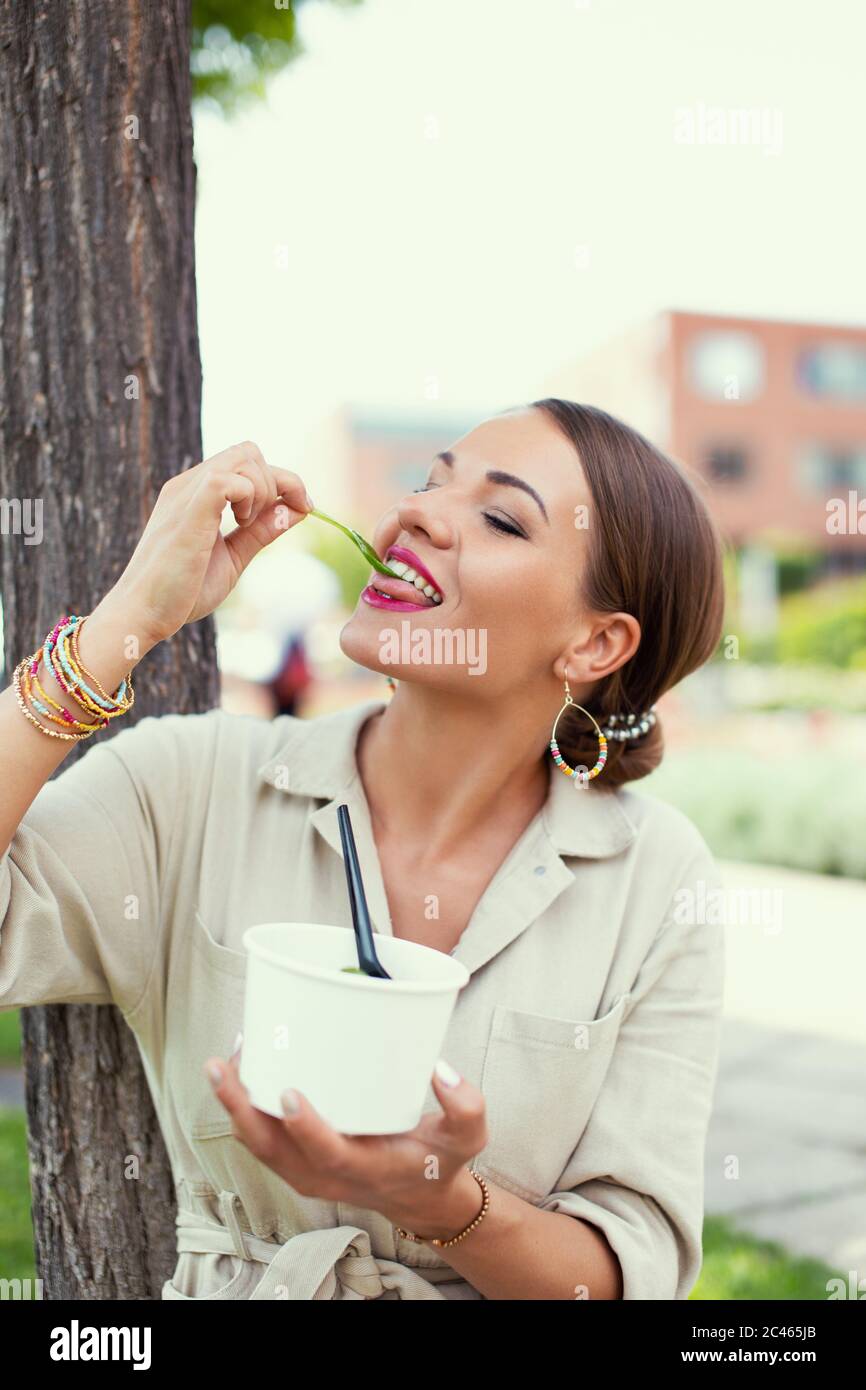 Giovane donna Latina che ama mangiare lattuga fresca al parco, stare Foto Stock