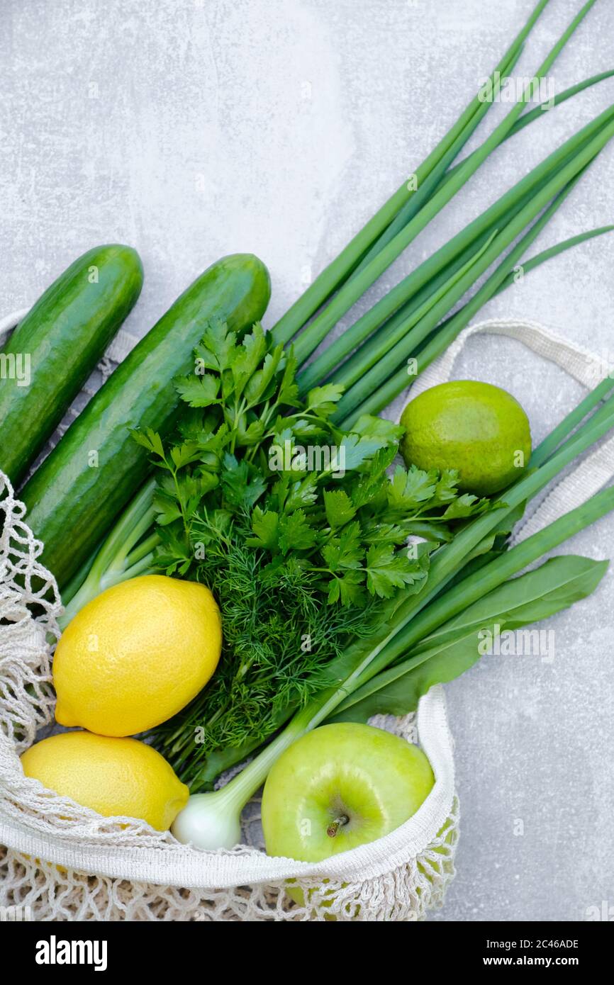 Borsa a rete riutilizzabile ed ecologica con verdure fresche e frutta su tavola in pietra. Vista dall'alto. Concetto di fornitura di alimenti per la salute Foto Stock