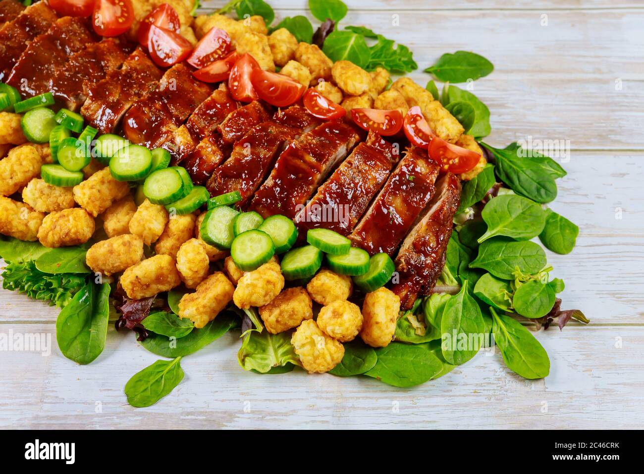 Costolette di ricambio alla griglia con insalata verde, potado e pomodoro. Foto Stock