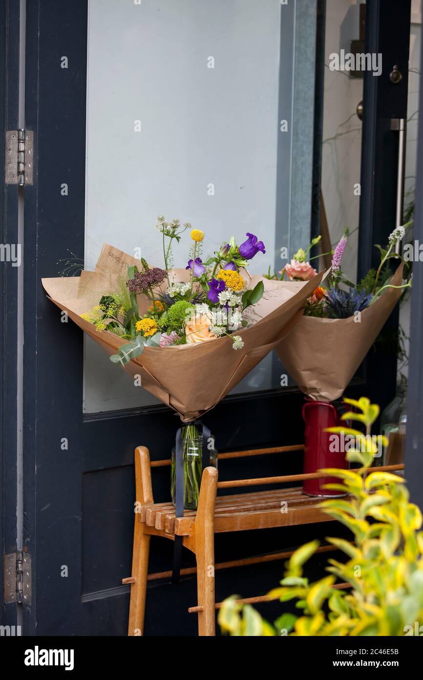 Londra, Regno Unito - 17 luglio 2019, Columbia Road Flower Market . Bouquet di fiori con campane avvolte in carta grigia artigianale in brocche su un carrello davanti a t. Foto Stock