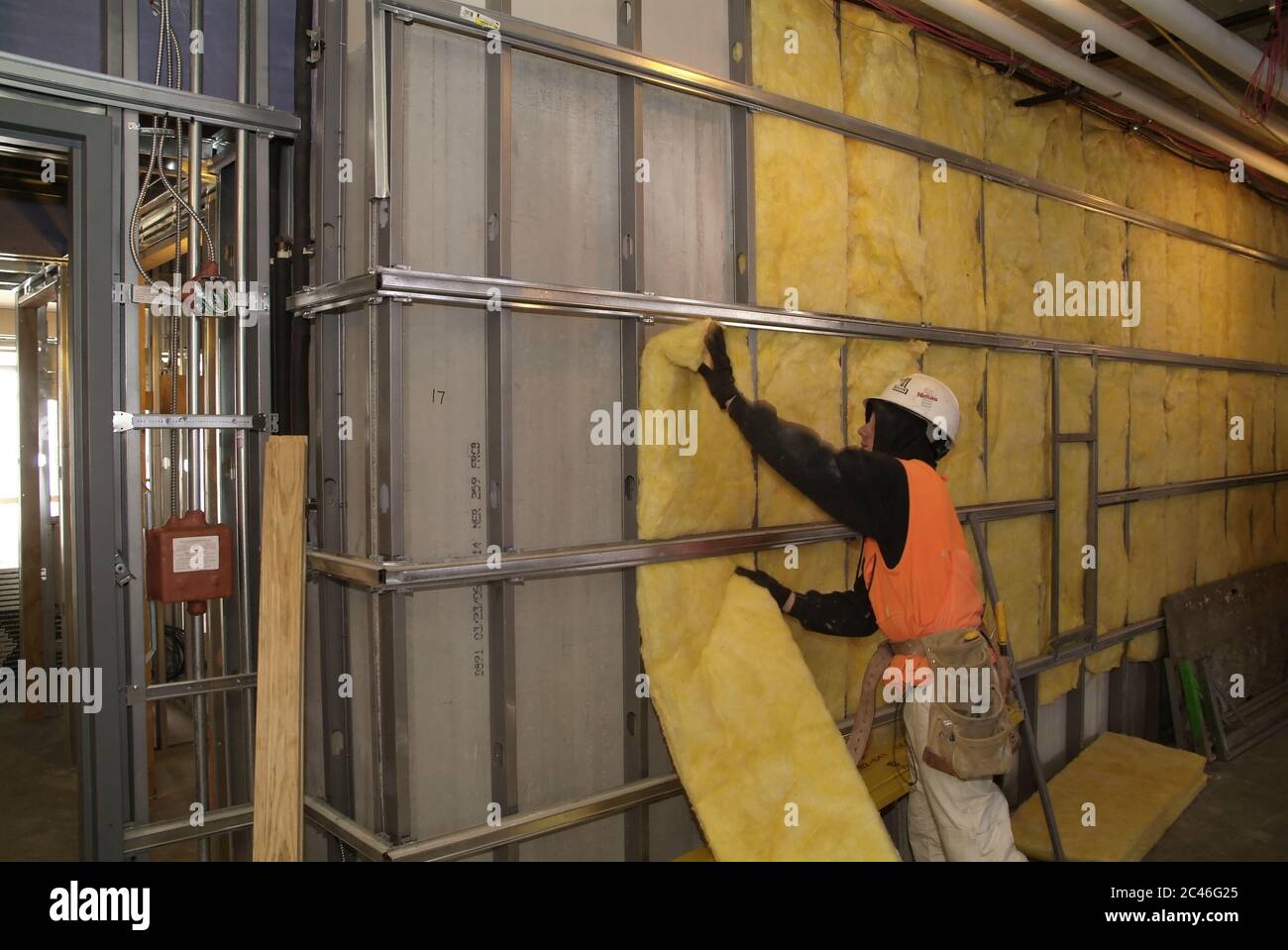 ST. CHARLES, STATI UNITI - 23 dicembre 2008: Un lavoratore di costruzione installa isolamento di parete di vetroresina in un edificio commerciale in costruzione Foto Stock