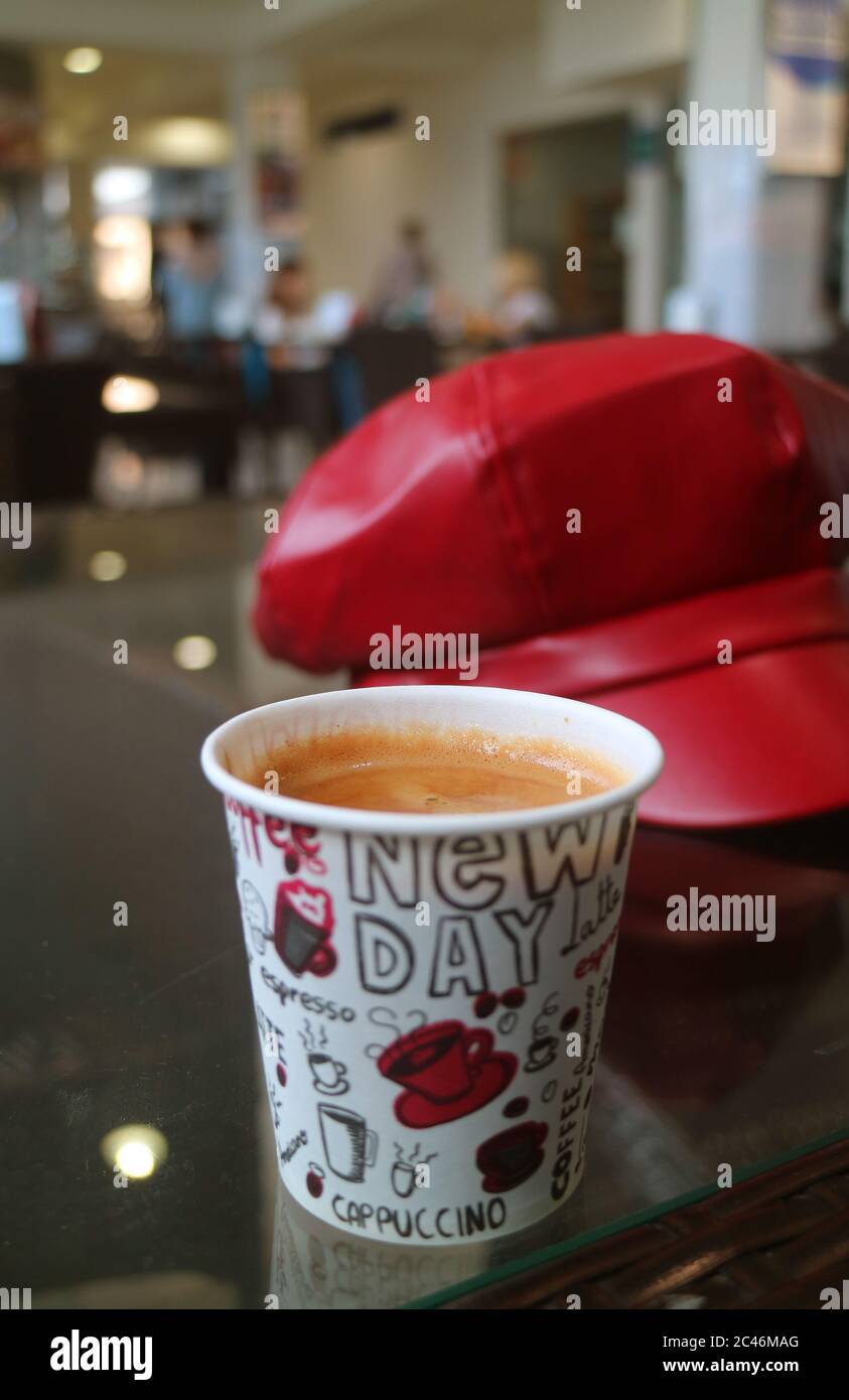 L'immagine verticale di caffè caldo in un bicchiere di carta con sfocata cappuccio rosso nel contesto Foto Stock