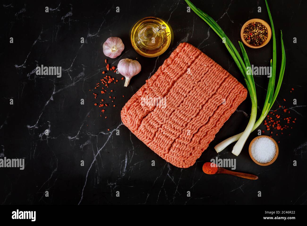 Olio d'oliva, aglio, carne macinata, pepe e cipolla verde fresca. Ingredienti per cucinare il meatball. Vista dall'alto. Foto Stock