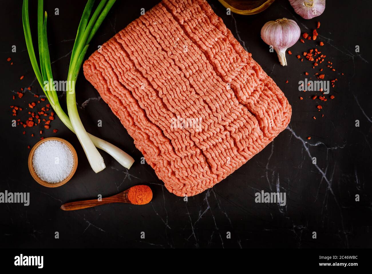 Macinato di manzo, aglio, pepe e cipolla verde fresca. Ingredienti per cucinare il meatball. Vista dall'alto. Foto Stock