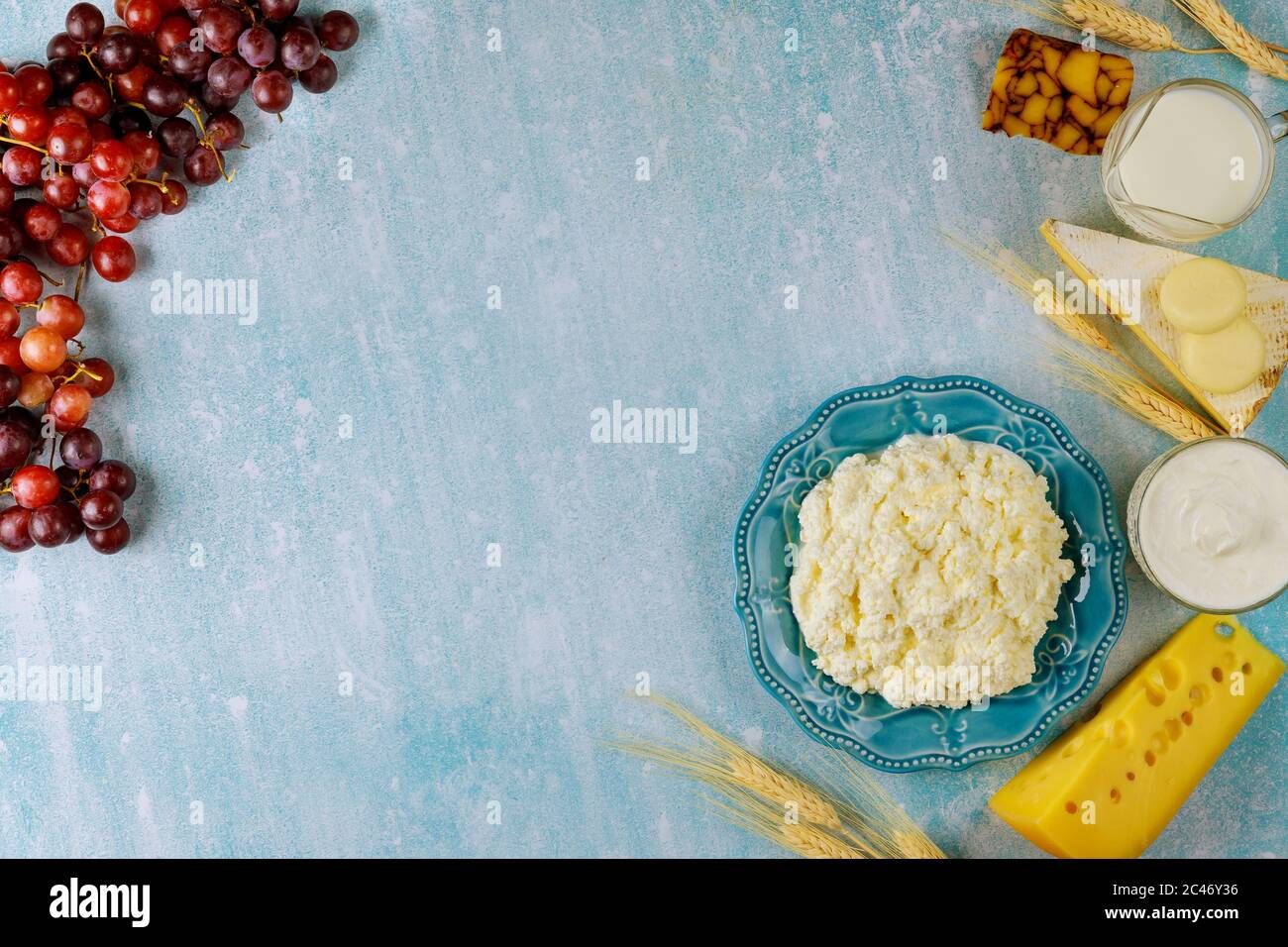 Ricotta formaggio, latte, grano e uva su sfondo blu. Shavuot concetto di vacanza ebraica. Foto Stock