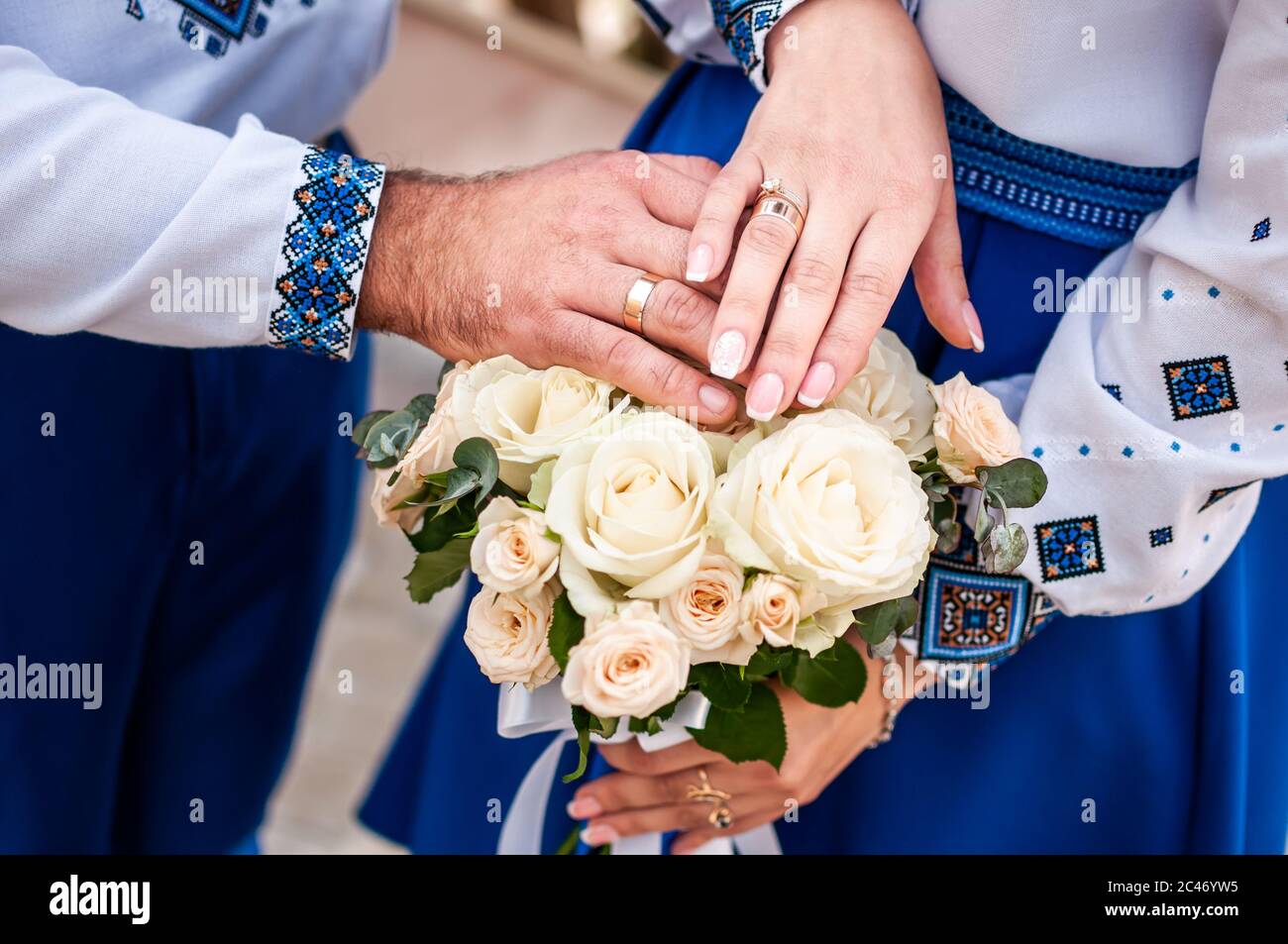Sposo e sposa che tengono le mani sul bouquet di fiori Foto Stock