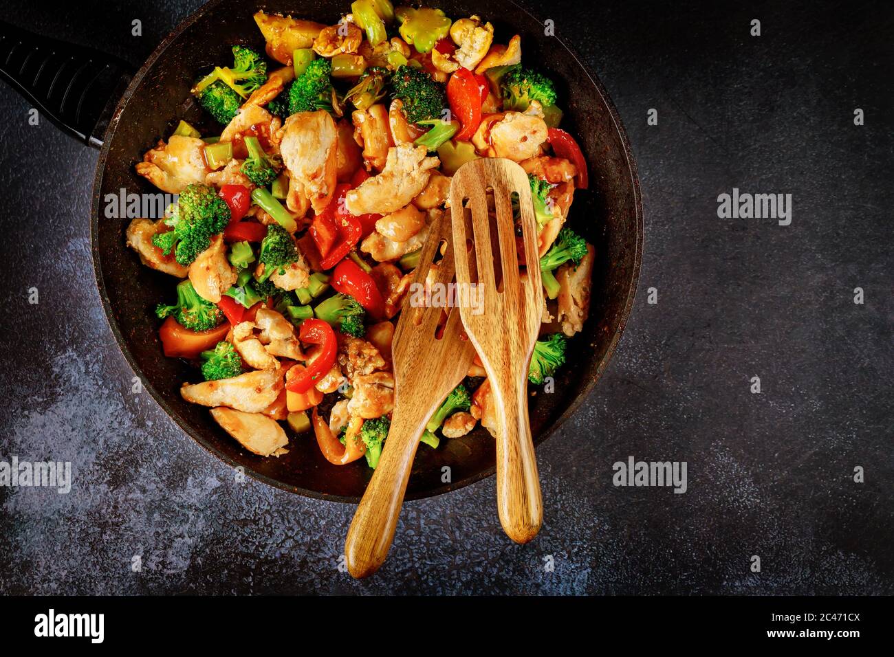 Deliziose verdure sane e fritte con pollo in padella su superficie scura. Foto Stock