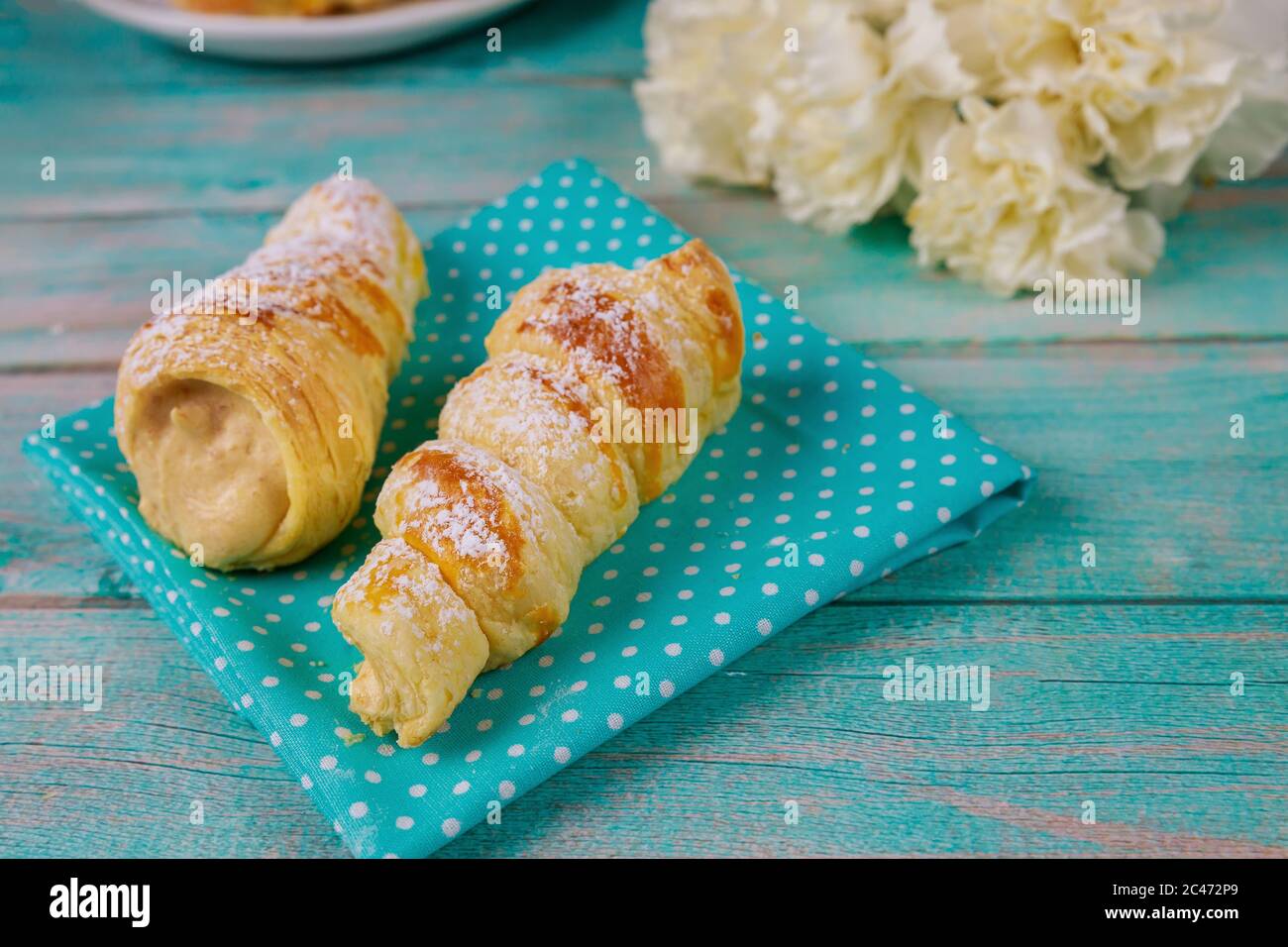 Panini di pasta sfoglia ripieni di crema dolce e fiori. Foto Stock