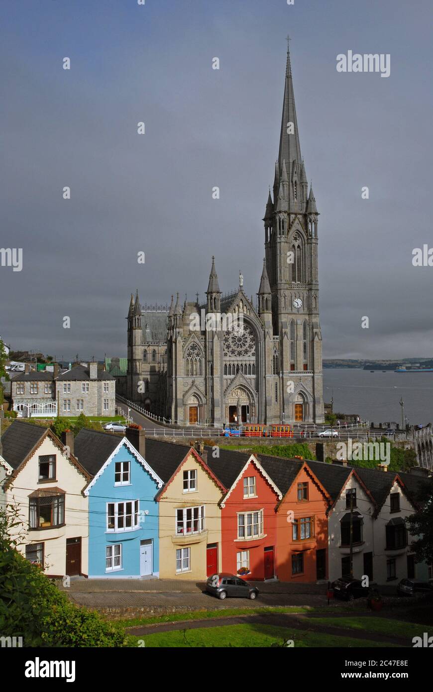 CATTEDRALE DI ST COLMANS e le colorate case in primo piano saturate dal sole della tarda estate, COBH, County CORK, IRLANDA Foto Stock