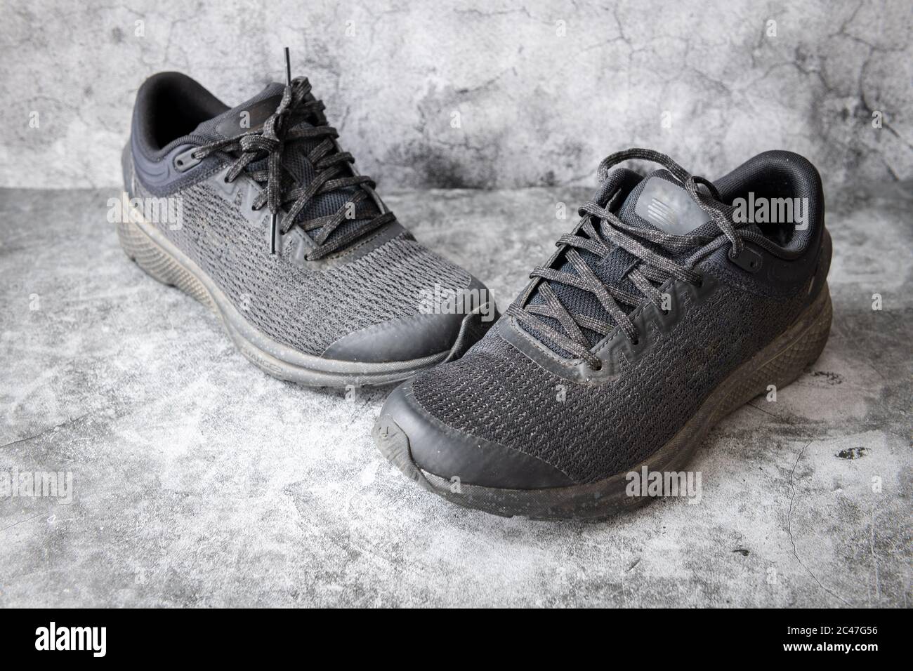 Un paio di scarpe da running nere su fondo grigio in cemento. Foto Stock