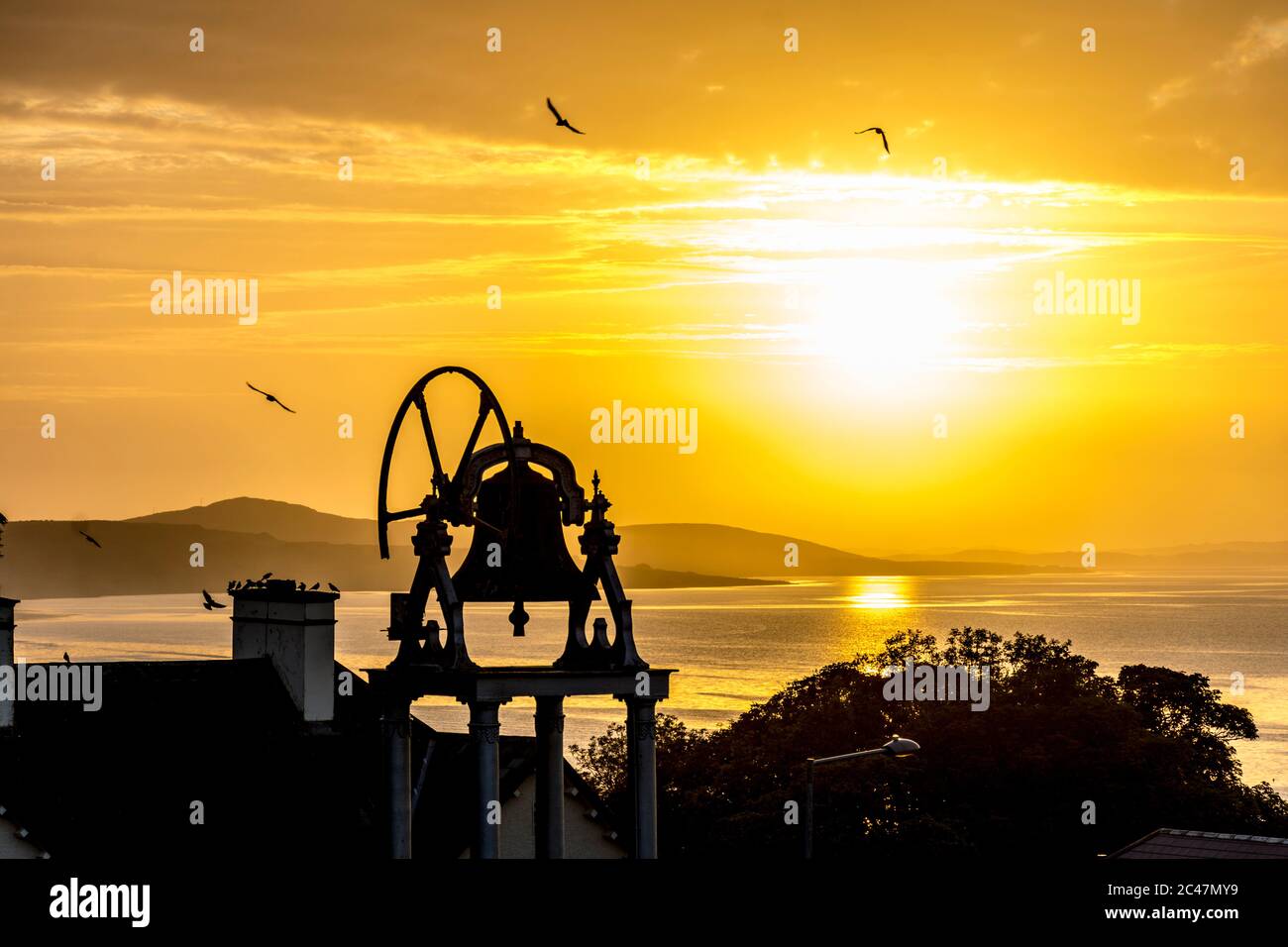 Ardara, Contea di Donegal, Irlanda 24 giugno 2020. Il sole tramonta sul villaggio costiero dell'Oceano Atlantico che si staglia sulla torre campanaria della chiesa. Foto Stock