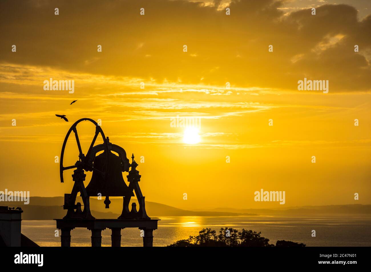 Ardara, Contea di Donegal, Irlanda 24 giugno 2020. Il sole tramonta sul villaggio costiero dell'Oceano Atlantico che si staglia sulla torre campanaria della chiesa. Foto Stock