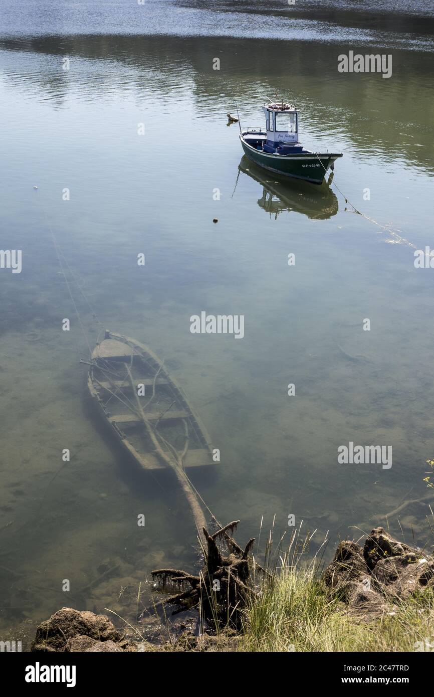 Scatto ad angolo alto di una piccola barca parcheggiata con un barca sommersa in primo piano Foto Stock Scatto ad angolo alto di una piccola barca parcheggiata con un barca sommersa in primo piano Foto Stock