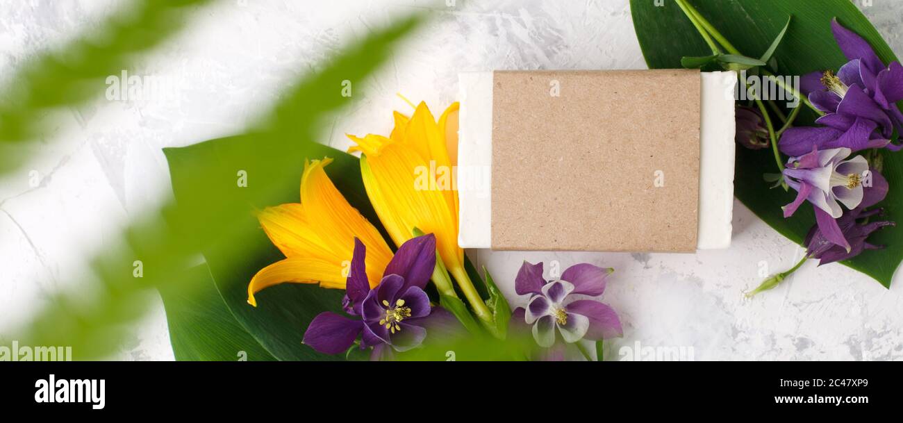 Sapone solido cosmetico o shampoo bars prodotto in artigianato, fiori su sfondo bianco. Concetto di bellezza naturale organica. Medicina di erbe, self-care messo a fuoco, Foto Stock