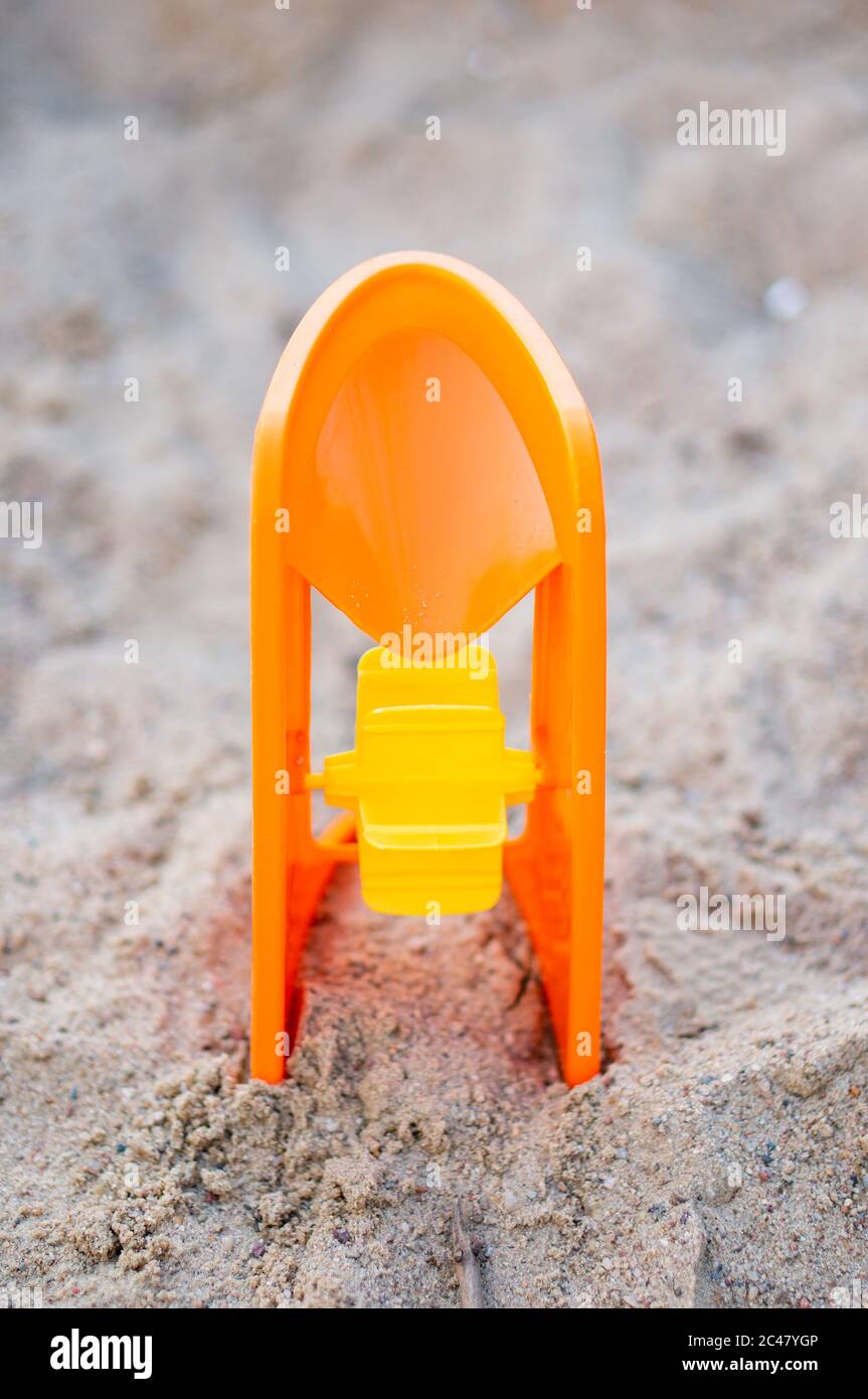 Colpo verticale di plastica arancione giocattolo mulino su sabbia Foto Stock